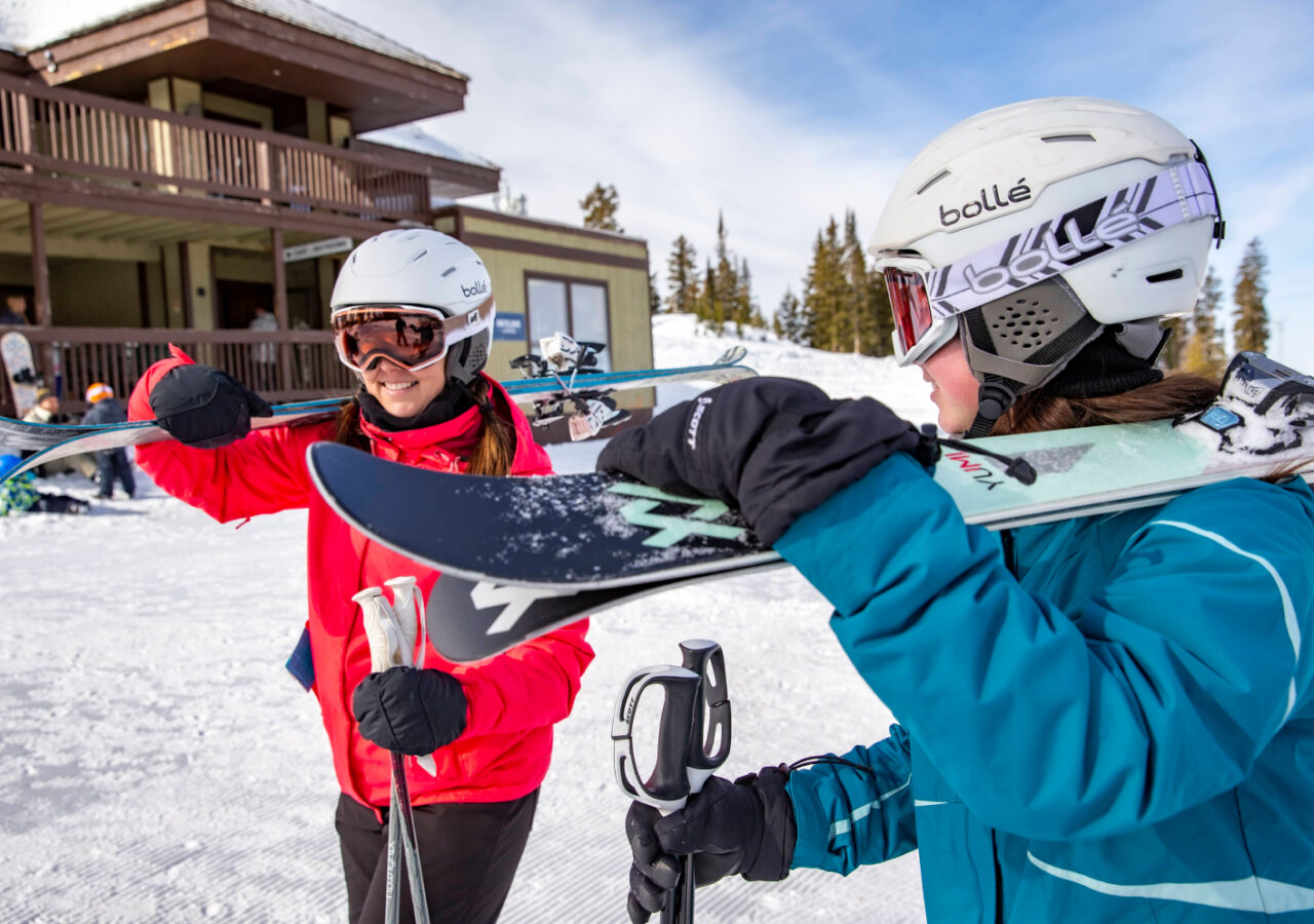 two people walking in the snow with skiis