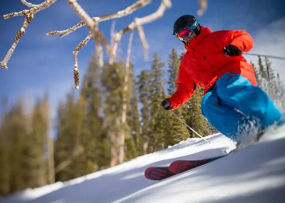 man in bright orange jacket sking down a mountain