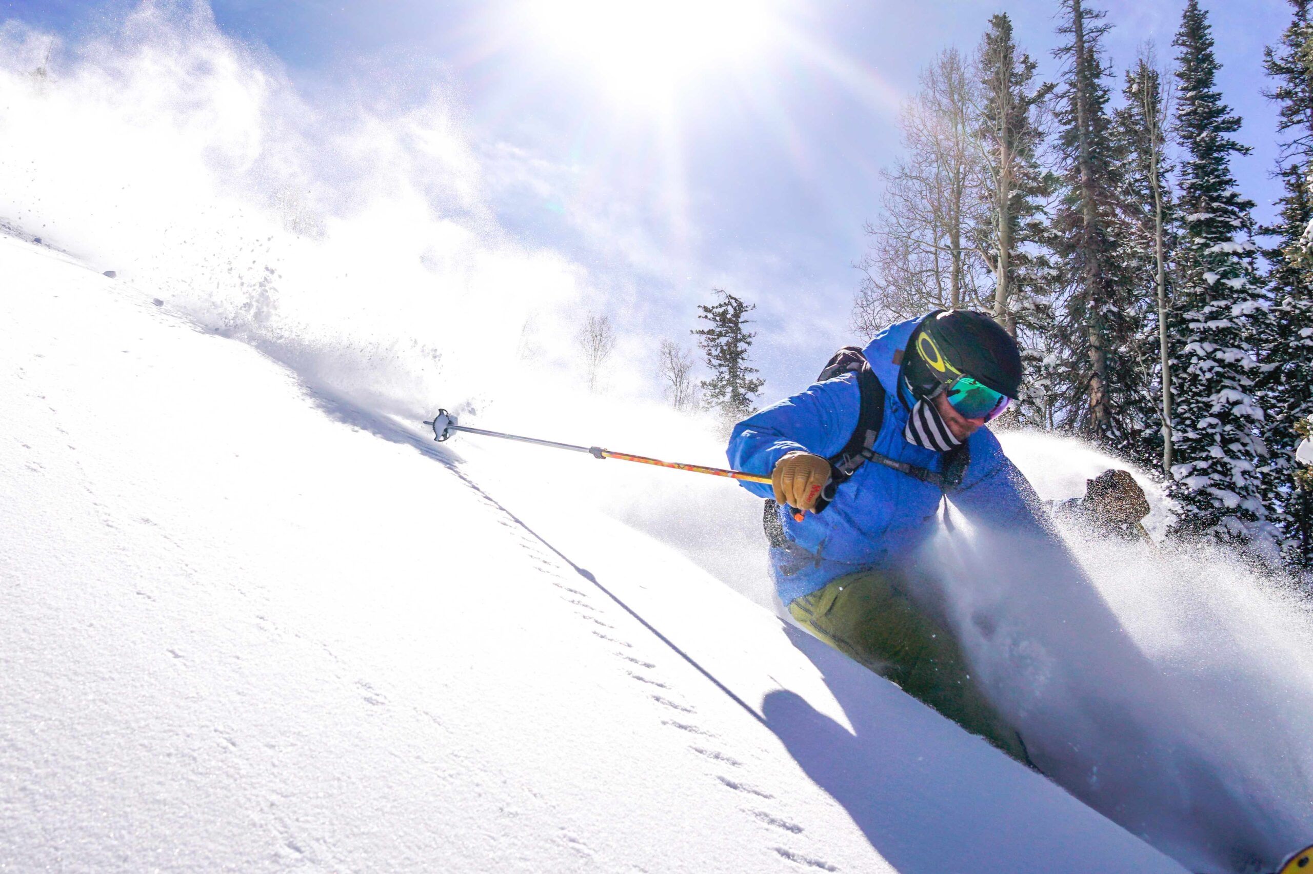 skier going down a snowy slope with powder in the air